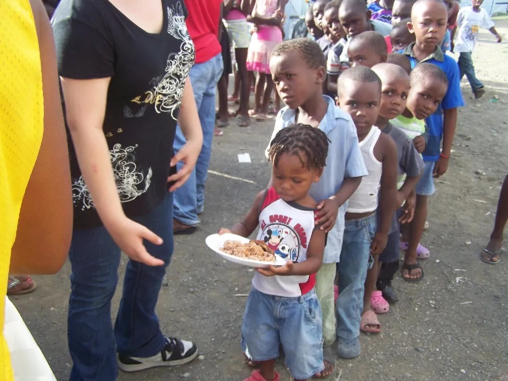 A group of children standing in line holding plates.