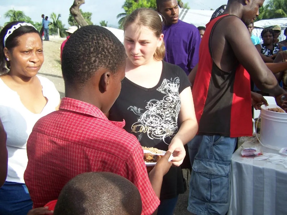 A woman is holding something in her hand while talking to some people.