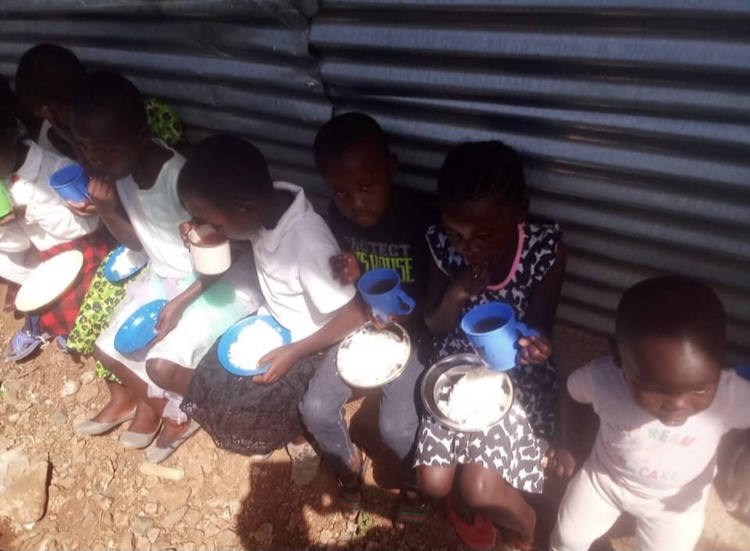 A group of children sitting around eating food.